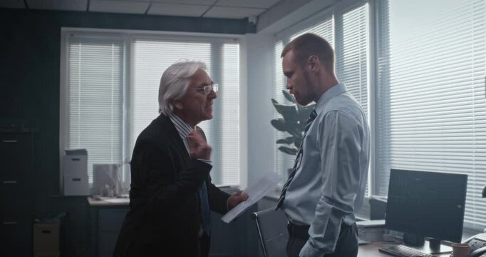 In modern office of bank: Irritated and angry boss having fight with male company employee over unsuccessful business deal. Senior team leader with papers loses temper and yells at man. Slow Motion.