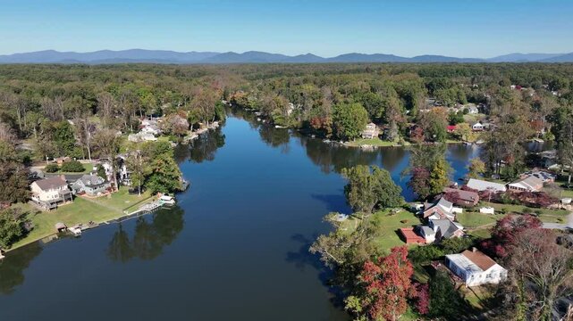 Descend drone shot of Timber Lake in Virginia State with luxury homes and villas. Beautiful autumn day and mountain range in background. Suburb district of american town.