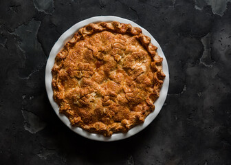 Traditional Irish closed apple pie on a dark background, top view