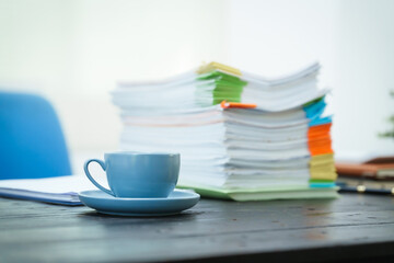 An empty office desk is cluttered with numerous documents and scattered coffee cups.The scene reflects a busy work environment, highlighting the ongoing tasks and the need for organization and focus