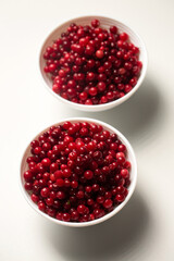Two bowls of red lingonberries on a white background. Top view