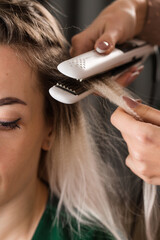 Fototapeta premium A stylist uses a curling iron to add volume