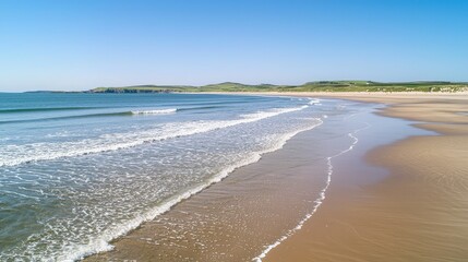 Obraz premium Serene Beach with Gentle Waves Under Clear Blue Sky