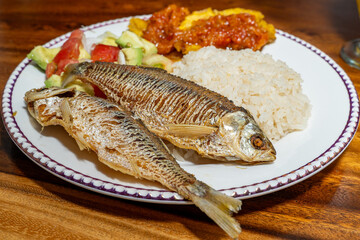 Exquisite Colombian dish with fish, coconut rice, salad and plantain with orange juice on a wooden table. Colombian gastronomy, typical dish.