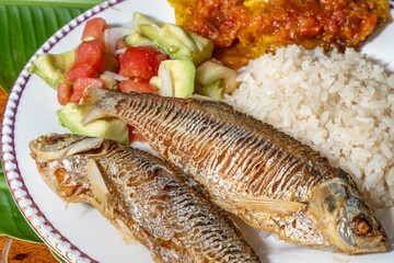 Exquisite Colombian dish with fish, coconut rice, salad and plantain with orange juice on a wooden table. Colombian gastronomy, typical dish.
