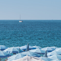 white and blue chairs on the beach and a white yacht in the see