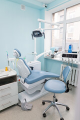 Modern dental clinic interior with a patient chair, equipment, and bright blue walls, perfect for oral health care