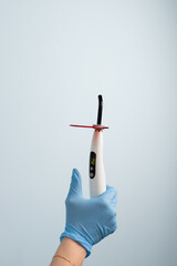 A dental professional holds a modern dental curing light in a clean dental clinic environment during a patient procedure