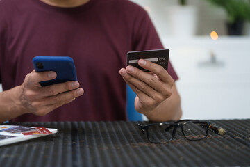 A businessman sits at a table, using his credit card to make an online payment on his laptop. He enjoys a lifestyle of frequent travel, shopping, and smart financial habits for wellness