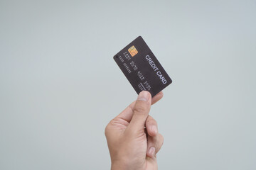 A close-up of a man’s hand holding a bank credit card against a white background, emphasizing secure online payment services and financial convenience for shopping and banking transactions