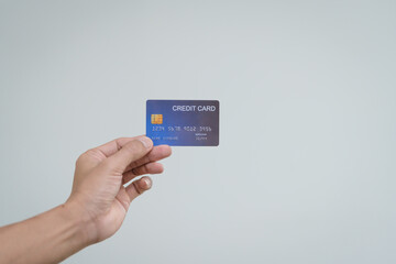 A close-up of a man’s hand holding a bank credit card against a white background, emphasizing secure online payment services and financial convenience for shopping and banking transactions