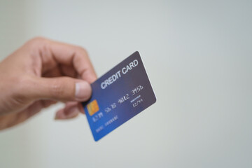 A close-up of a man’s hand holding a bank credit card against a white background, emphasizing secure online payment services and financial convenience for shopping and banking transactions