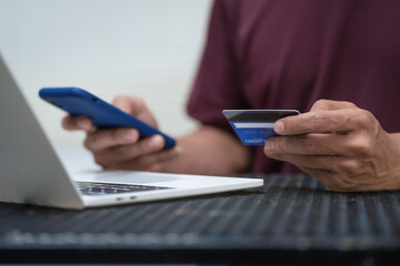 Fototapeta premium Close-up of a man's hand holding a bank credit card, highlighting online services for lending and access to credit,demonstrating financial convenience and flexibility for secure digital transactions
