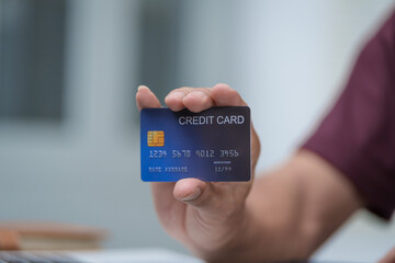 Close-up of a man's hand holding a bank credit card, highlighting online services for lending and access to credit,demonstrating financial convenience and flexibility for secure digital transactions