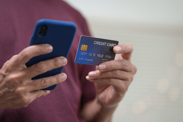 Close-up of a man's hand holding a bank credit card, highlighting online services for lending and...