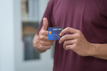 Close-up of a man's hand holding a bank credit card, highlighting online services for lending and access to credit,demonstrating financial convenience and flexibility for secure digital transactions