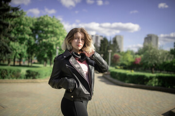 Portrait of a young beautiful girl in a black jacket in an urban environment.