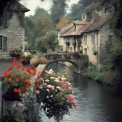Fototapeta premium Charming Stone Village with Flower Lined Bridge Over Shimmering Riverside