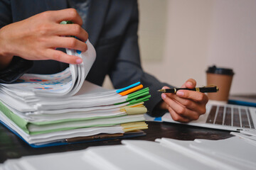 A businessman works late at his desk, focused on his laptop while talking online. He checks important financial documents, demonstrating dedication and diligence as he manages his overtime tasks