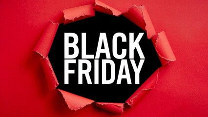 A black background with the words Black Friday in white text is revealed through a torn hole in a red textured paper.