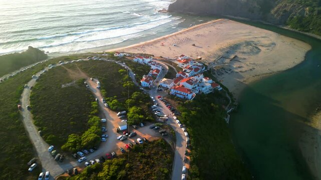 Drone shot over Praia de Odeceixe small coastal village with beach view at sunset