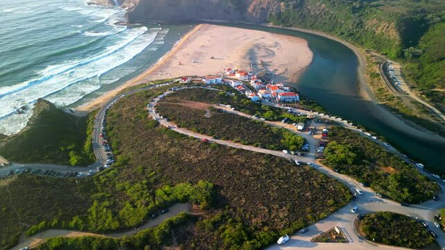 Drone shot over Praia de Odeceixe small coastal village with beach view at sunset