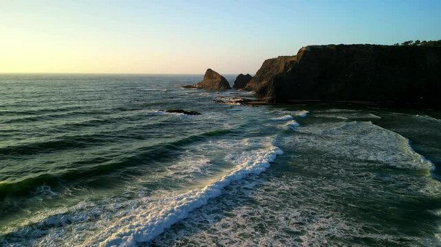 Drone shot over Praia de Odeceixe beach with coastal hills and sea view at sunset