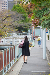 秋の昼の住宅地の道路で歩く一人の若い女性の姿