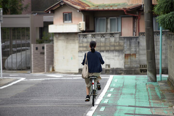 秋の昼の静かな住宅街で自転車を乗る一人の若い女性の姿