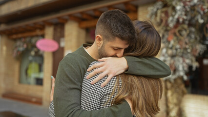 Affectionate man and woman embracing on a busy urban street, showcasing love and a close relationship in an outdoor setting.