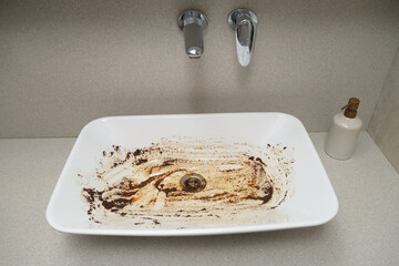 Dirty white sink in the bathroom after a clogged pipe. Ceramic washbasin in dirty rust