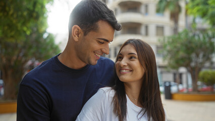 Obraz premium Man and woman smiling together in an urban park, showcasing their relationship and beautiful connection in an outdoor city setting.