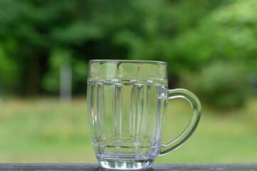 Pusty kufel z uchem o dużej pojemności na tle zieleni w ogrodzie  © Paweł Kacperek