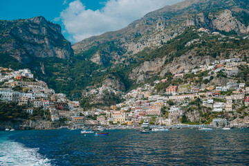 Fototapeta premium View of colorful buildings on the cliffs of Positano, Italy, with boats anchored in the blue Mediterranean waters..