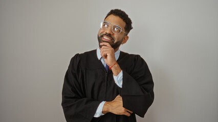 Young man in a graduation robe looking up pensively against a white isolated background.