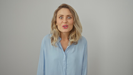 Obraz premium A surprised young caucasian woman with blonde hair wearing a light blue shirt against a white background.