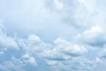 Fluffy white clouds drift across a vast expanse of clear blue sky