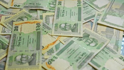 Bangladeshi banknotes scattered on a surface, highlighting various denominations of taka from bangladesh in vibrant green and yellow hues.