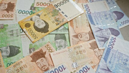 Obraz premium South korean banknotes scattered closely, showcasing various denominations of the south korean won.