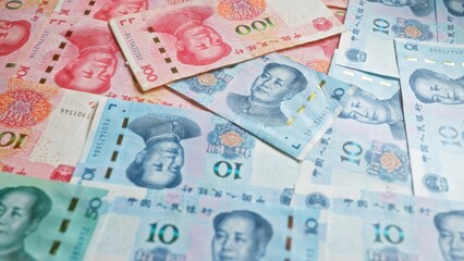 Chinese yuan banknotes scattered across a surface, highlighting various denominations and the face of mao zedong, symbolizing china's financial and economic system.