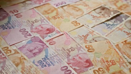 Turkish lira banknotes scattered across a surface in turkey, displaying various denominations and detailed designs.