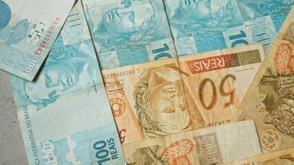 Brazilian banknotes of various denominations scattered, showcasing the vibrant design of the brazilian real currency in a close-up view.