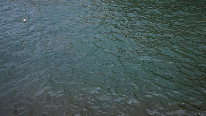 Serene water surface with gentle ripples and a single red buoy floating under natural light