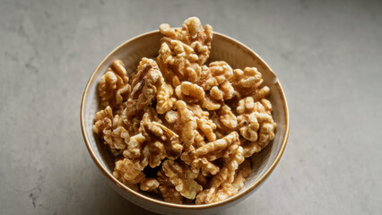 Bowl of walnuts placed on a grey surface showing the nutty texture and wholesome snack option perfect for healthy eating and organic food choice