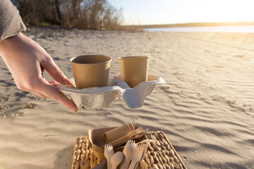 A pair of biodegradable paper cups on a paper tray, resting on a beach at sunset. The cups have space for customizable designs, great for eco-friendly branding, coffee shops, and sustainability campai