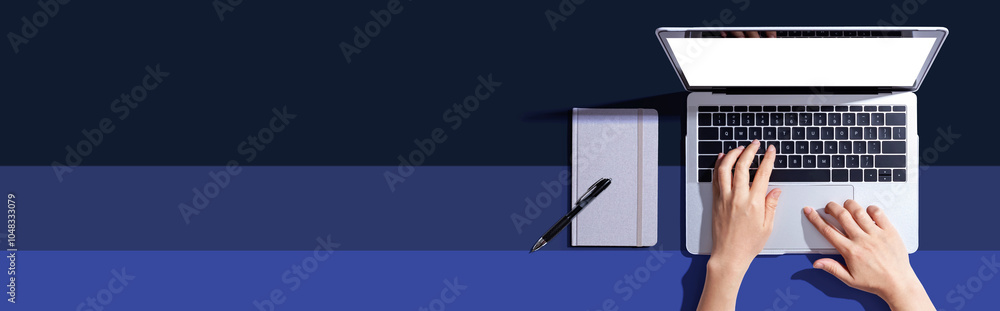 Poster person using a laptop computer with a notebook - flat lay