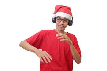 Portrait of excited Asian man in red t-shirt with santa hat enjoying and listening to music using headphone. Isolated image on white background