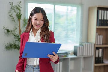 Fototapeta premium Attractive Asian businesswoman standing on the phone talking about real estate projects and chatting with happy smiles at the office.