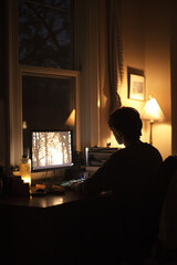 Fototapeta premium A person sitting at a desk late at night, illuminated by the glow of a computer screen