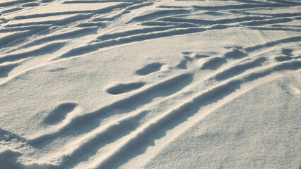 Footprints and car tire marks in the snow
